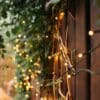 30m heavy duty warm white fairy lights showing the thick dark green cable and dense LED spacing against a fence.