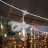 10m white festoon string lights with warm ST64 LED bulbs glowing outdoors
