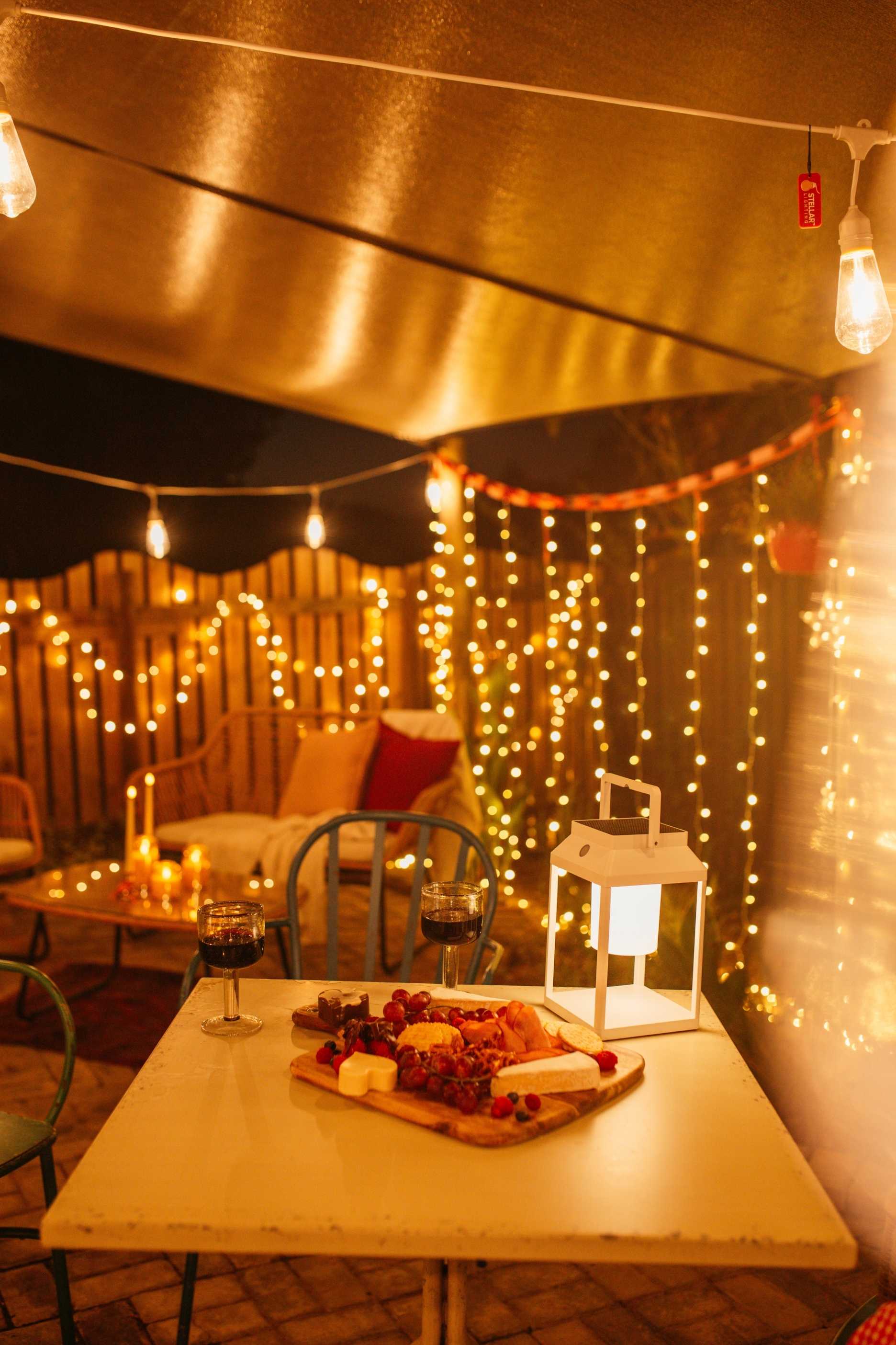 Romantic outdoor Valentine’s Day lighting with festoon lights, lanterns, and candles